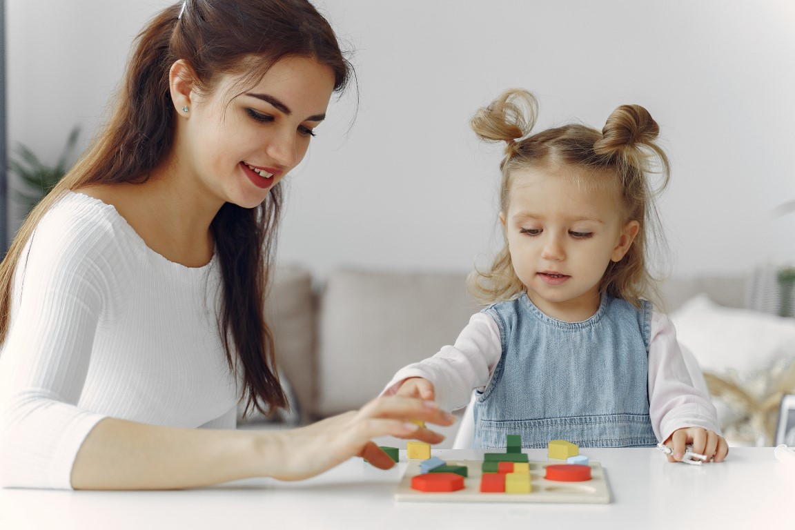 Tutor with pupil. Little girl studying. Private lesson. Mother plays with her daughter.